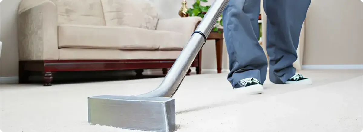 Carpet cleaning technician using a hot-water extraction wand on a light-colored carpet in a living room, Salt Lake City, UT.